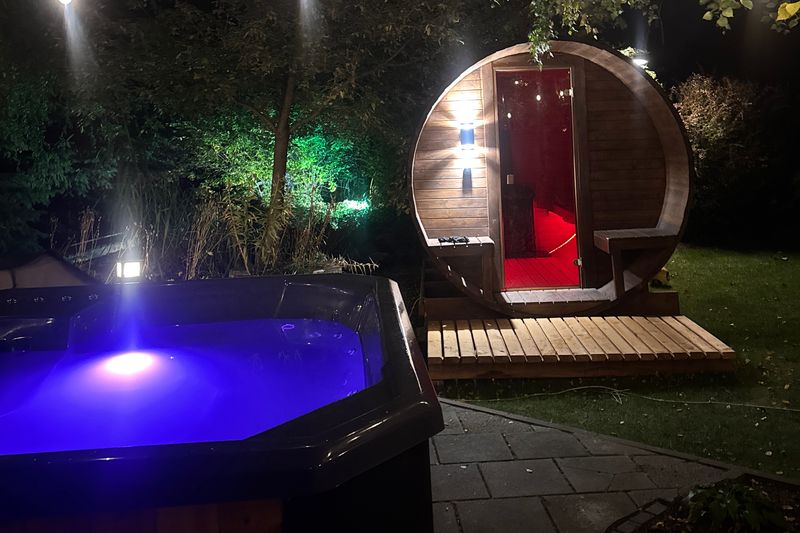 Balia kwadratowa z podświetleniem i Sauna Beczka w jednym ogrodzie, wieczorem