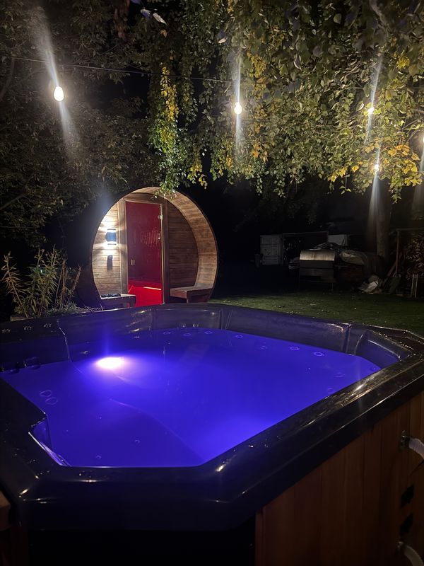 Podświetlona woda w balii kwadratowej, w tle Sauna Beczka