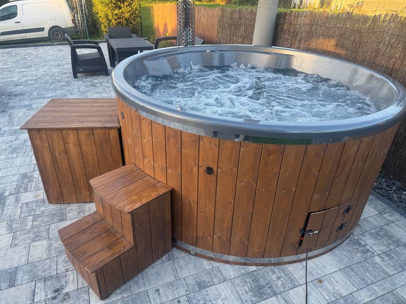 Hydromasaż w balii okrągłej: woda z bąbelkami, obok drewniane schodki