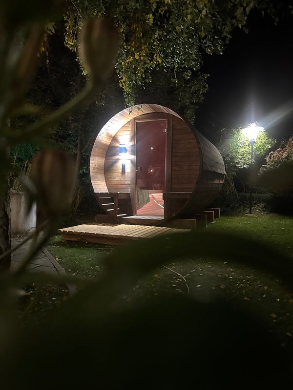 Podświetlona Sauna Beczka w ogrodzie nocą