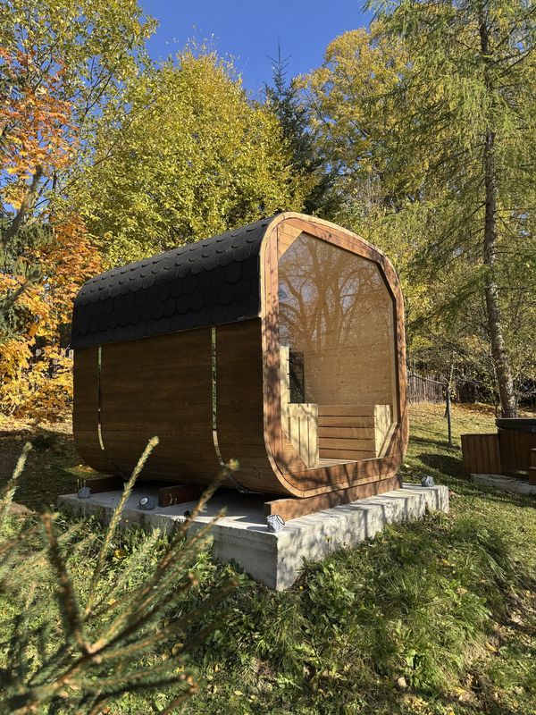 Sauna Quadro z panoramicznym oknem i dachem z gontu w jesiennym ogrodzie