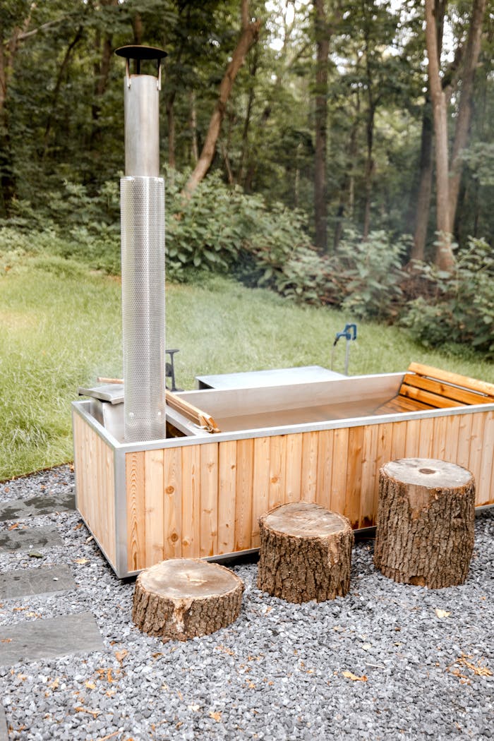 Usługi Relaxing wood-fired hot tub with stumps in a serene forest setting.