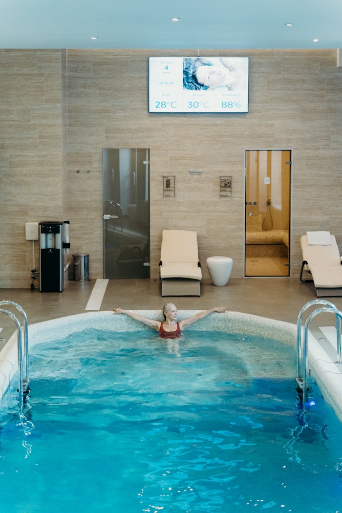 Usługi Woman enjoying leisure time in an indoor swimming pool, surrounded by modern amenities.